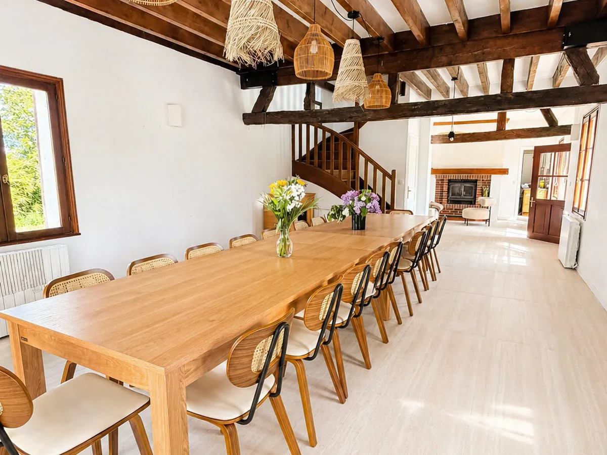 La même salle après travaux, grande table de vingt couverts sous les poutres
